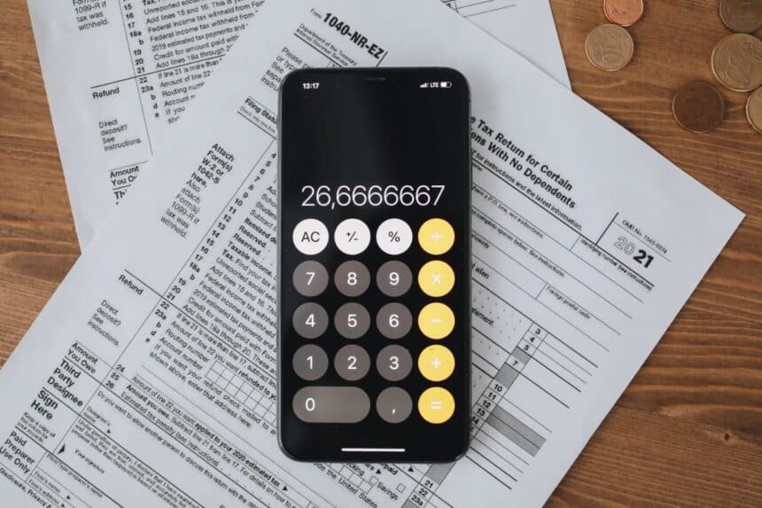 Tax forms and a calculator on a wooden desk, illustrating unpaid property tax bills in Denville