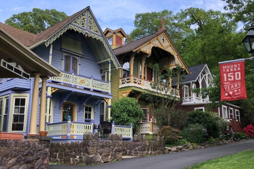 Colorful Victorian cottages along a Mount Tabor street with a red Mount Tabor 150 Years banner hanging from a lamppost