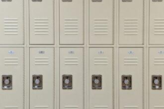 Row of beige lockers with combination locks in a school hallway