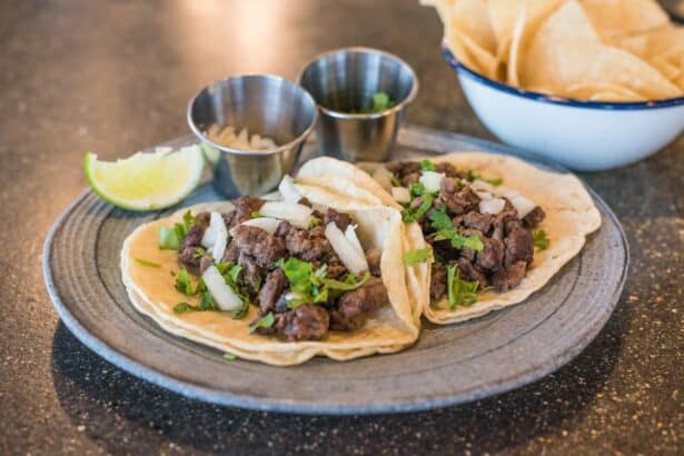 Beef tacos topped with onion and cilantro with a lime wedge