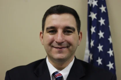 Michael Embrich, a U.S. Navy veteran and nominee for New Jersey's first Veteran Advocate, smiling in front of an American flag.