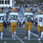 Morris Knolls Golden Eagles football captains in gold helmets and white jerseys walk to midfield for the coin toss
