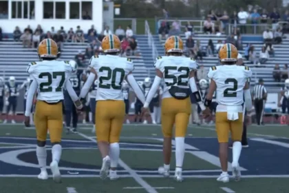 Morris Knolls Golden Eagles football captains in gold helmets walk to midfield for the coin toss