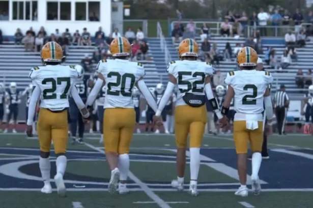 Morris Knolls Golden Eagles football captains in gold helmets walk to midfield for the coin toss