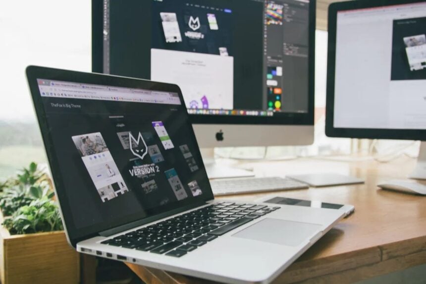 Laptop and desktop screens showing website design work